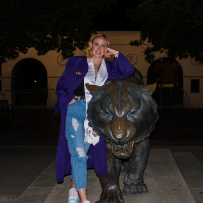 lexi daniels wearing graduation gown with the LSU tiger statue