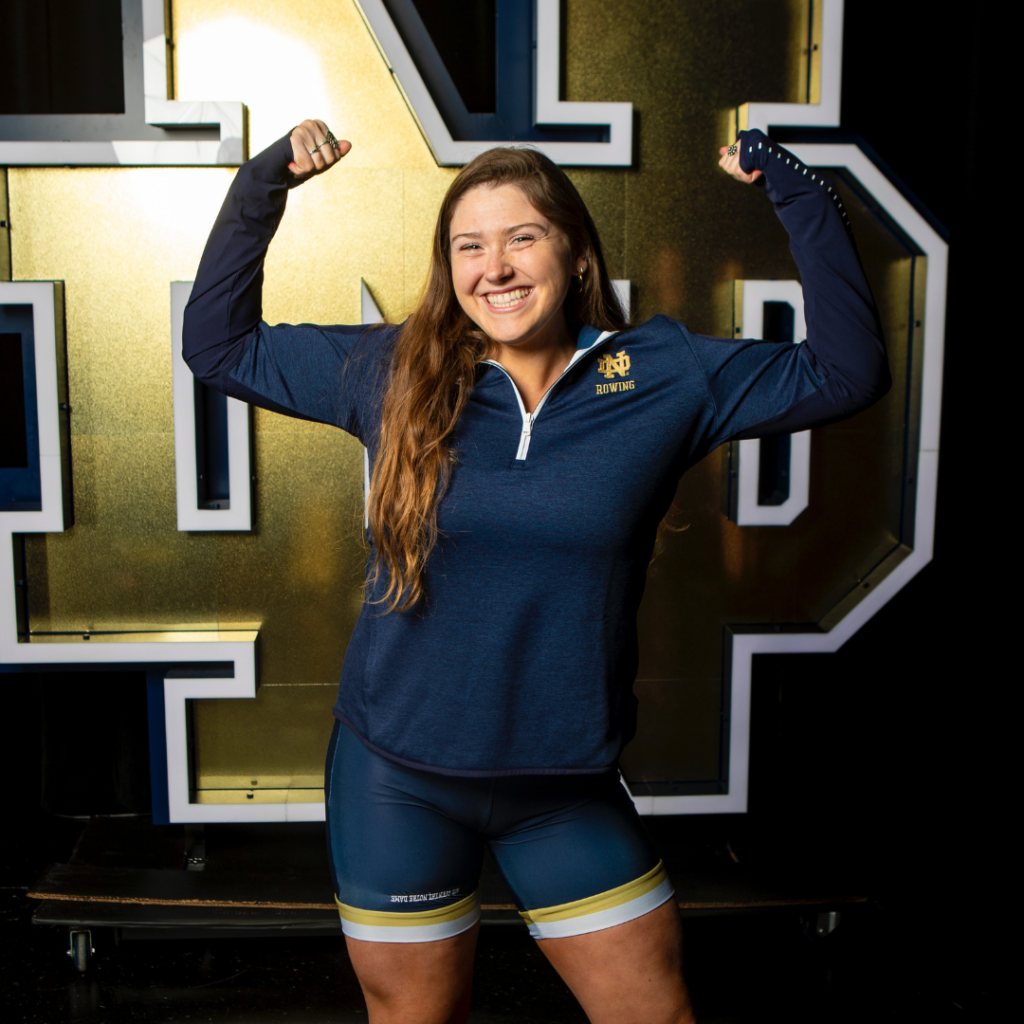Mariah Parsons standing in front of the Notre Dame logo and raising her arms