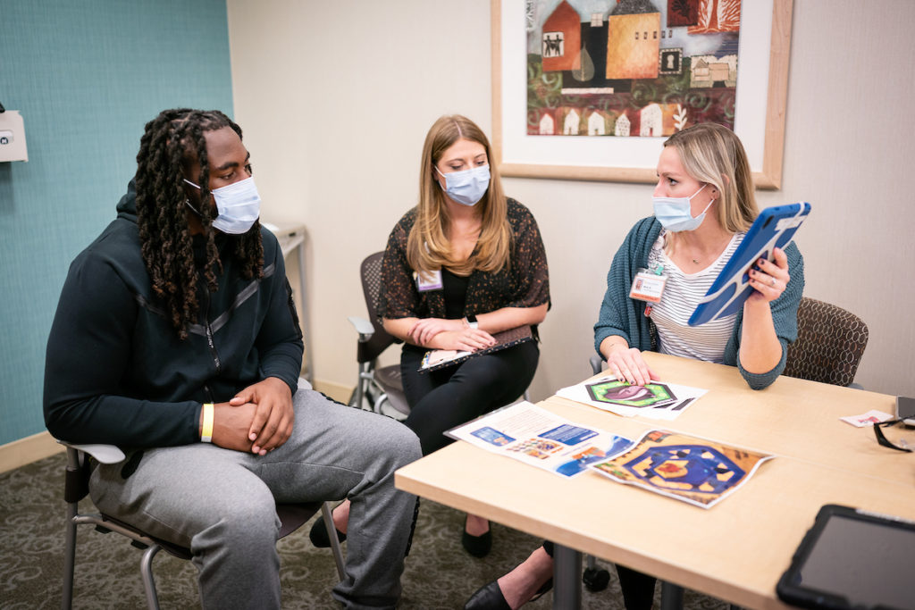 Patrick Jones sitting at a table with 2 others while touring Gillette Children's Specialty Hospital