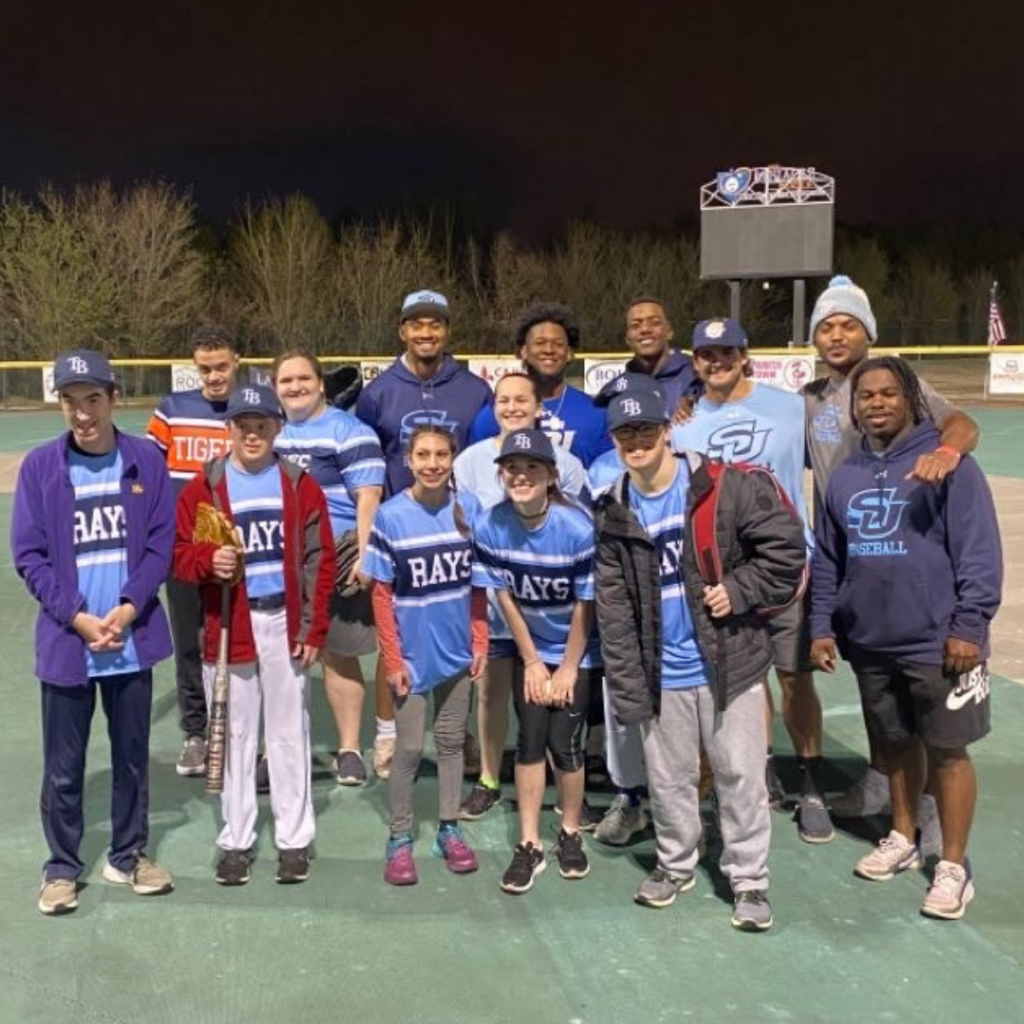 A group of athletes pose on a baseball field.