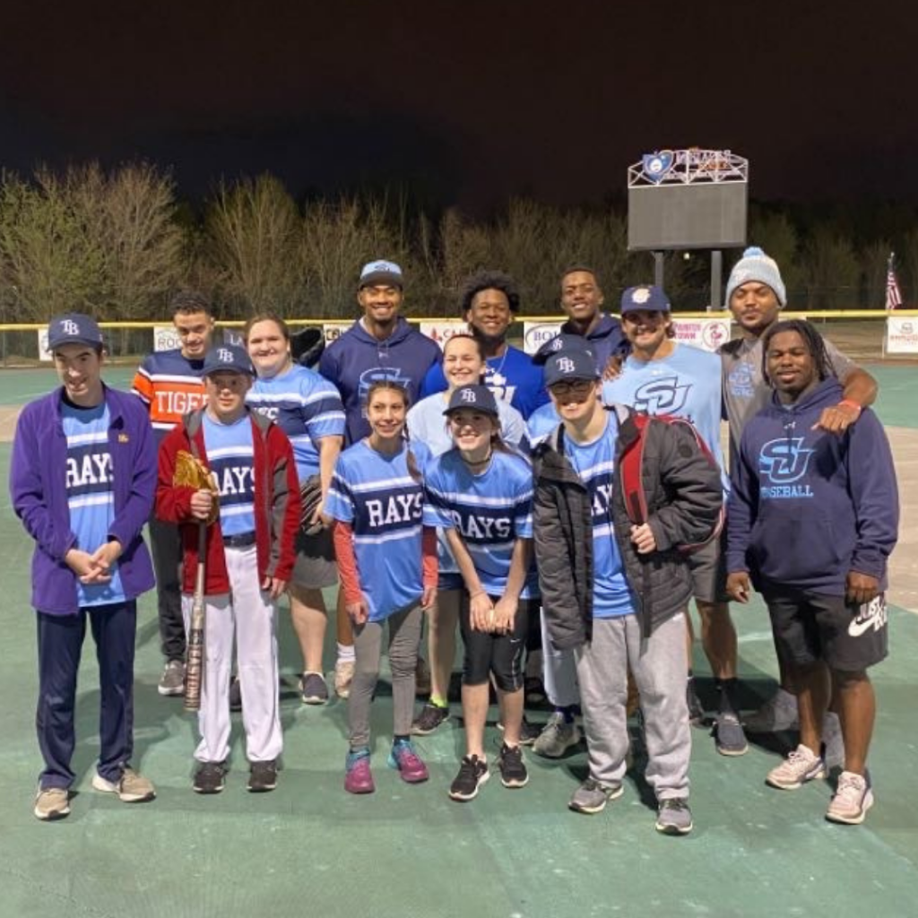 A group of athletes pose on a baseball field. 