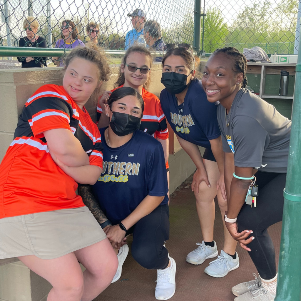 A group of athletes pose in a baseball dugout.