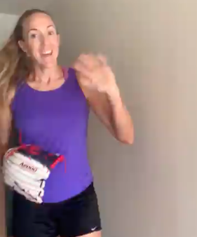 Monica Abbot smiling and waving while wearing a softball mitt. 