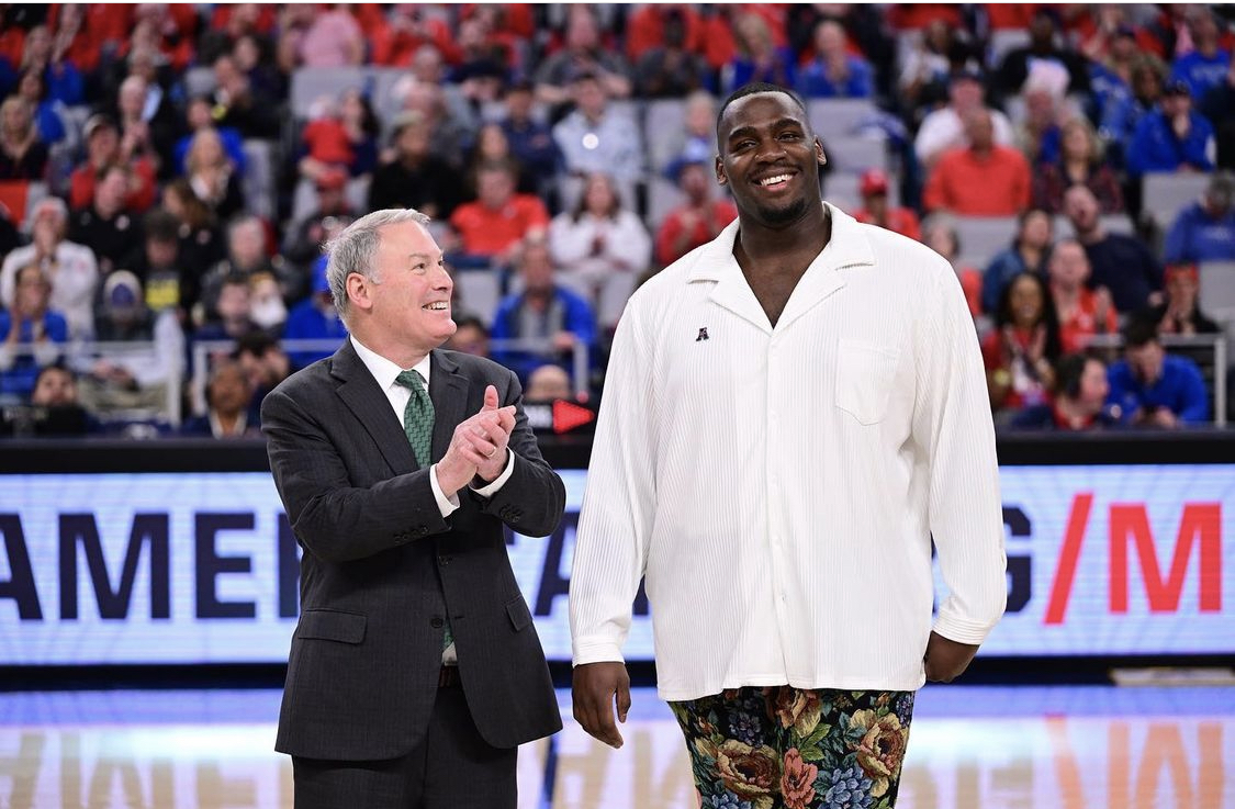 Chris Paul stands on a basketball court with a Tulsa administrator as Chris receives an on-court recognition