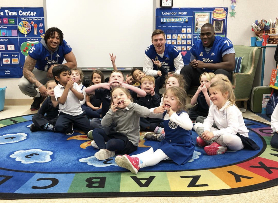 Tulsa football players pose with kids in a classroom