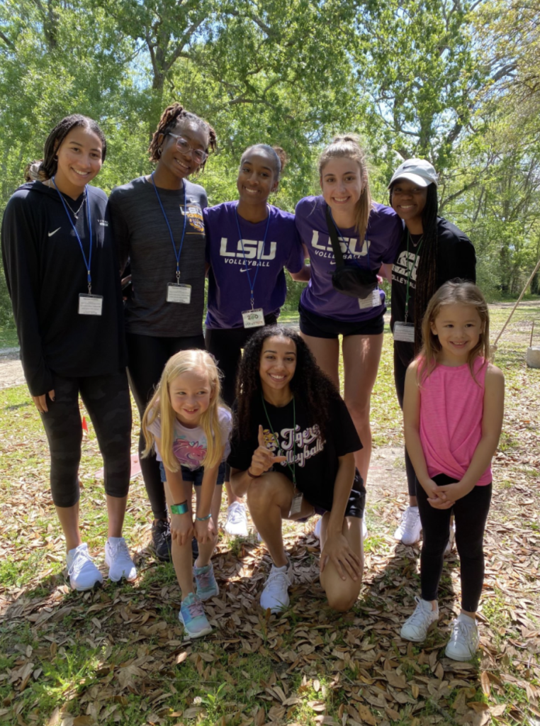 college athletes post with two children outside