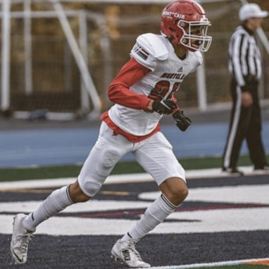 football player mid-stride, running out of the endzone with a referee in the background