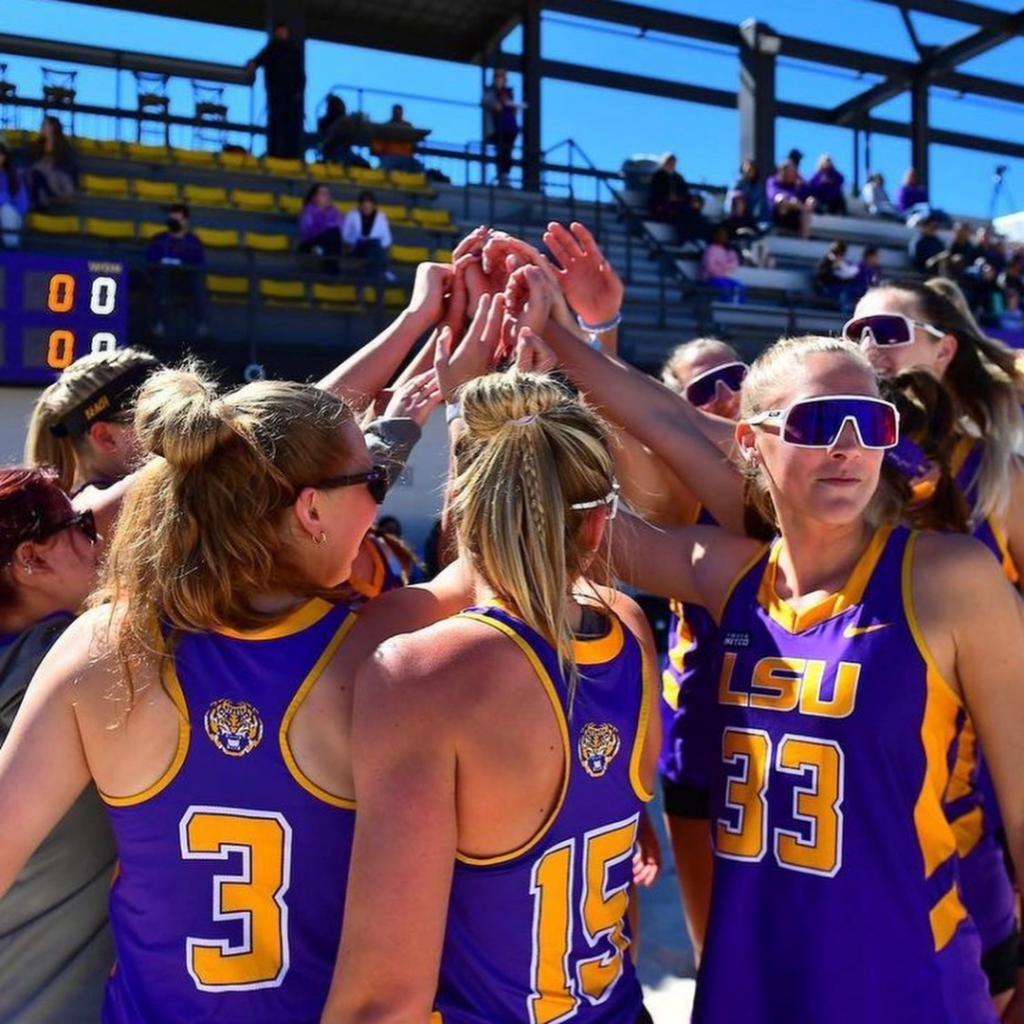 LSU Beach volleyball players putting their hands together in a huddle