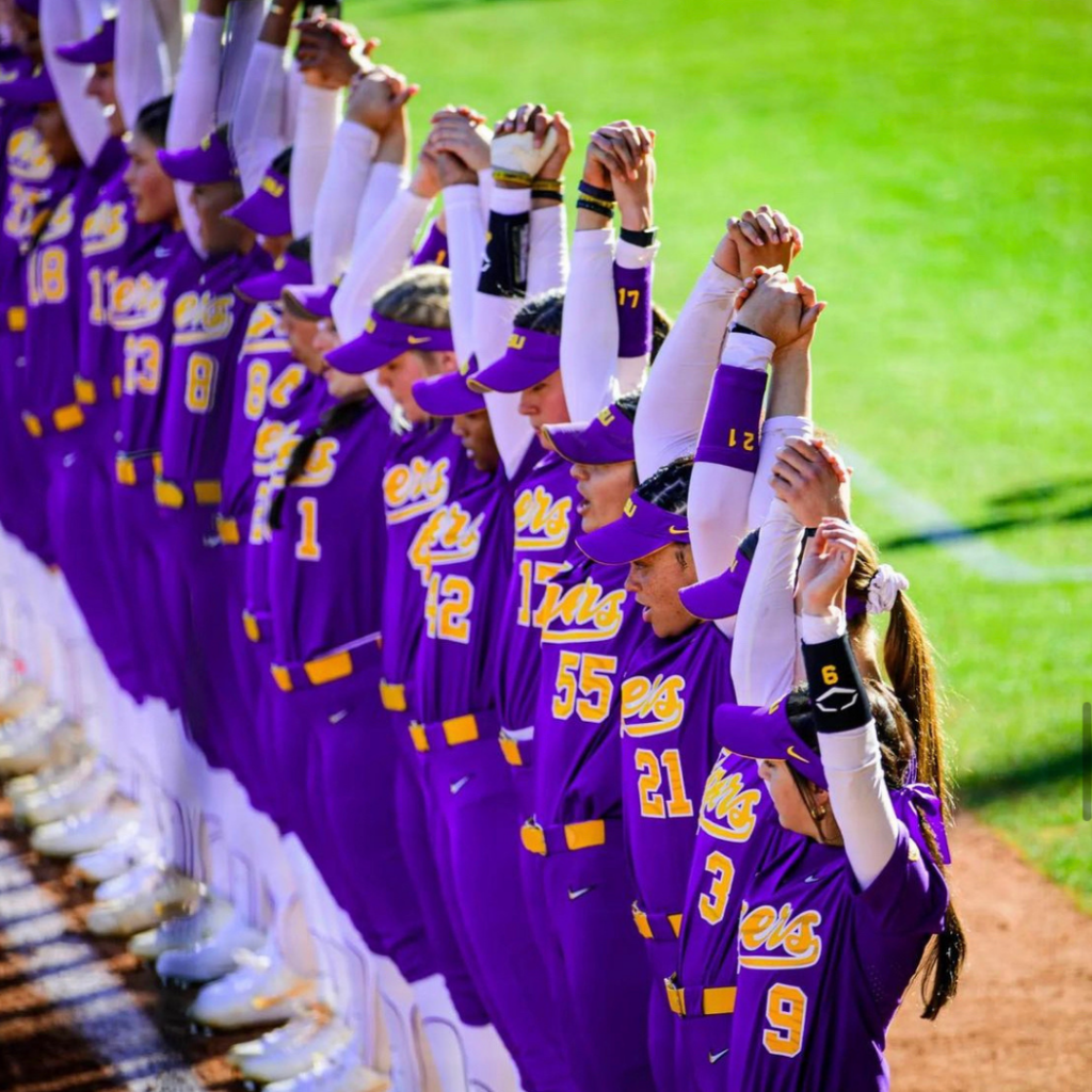 LSU softball players holding hands with their arms over the heads