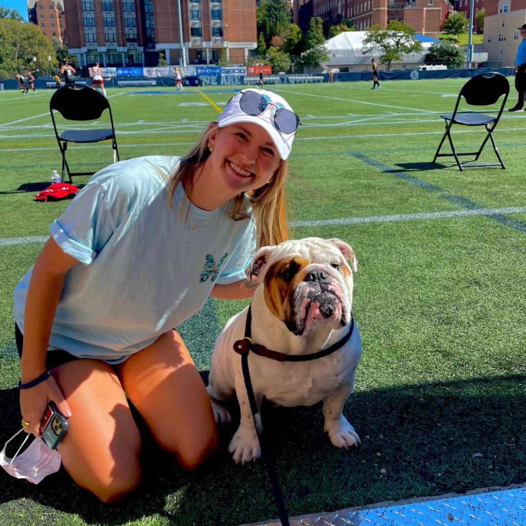 ruth axton poses with a bulldog on a turf field