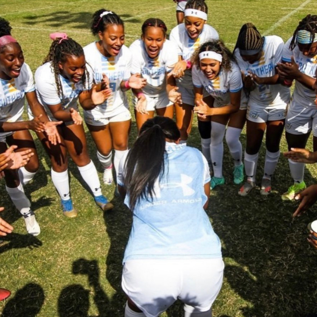 Southern soccer players huddled together cheering before a game on a grass soccer field