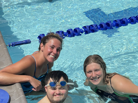 Tulane student-athletes and a Special Olympics athlete stand in the pool and smile at the camera.