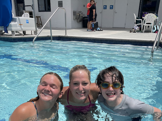 Tulane student-athletes and a Special Olympics athlete stand in the pool and smile at the camera.