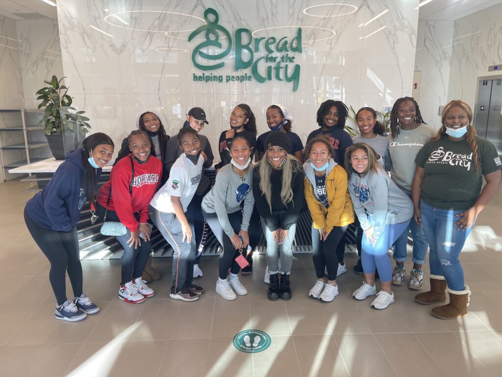 A group of howard university student-athletes stand in front of a bread for the city sign (inside).