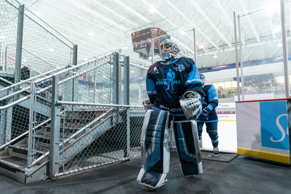 Terra wearing her hockey gear as she walks off the ice with the area behind her