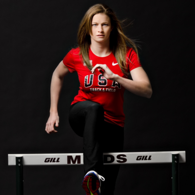 Image of Casey Zeller in USA track & field t-shirt posing jumping over a hurdle