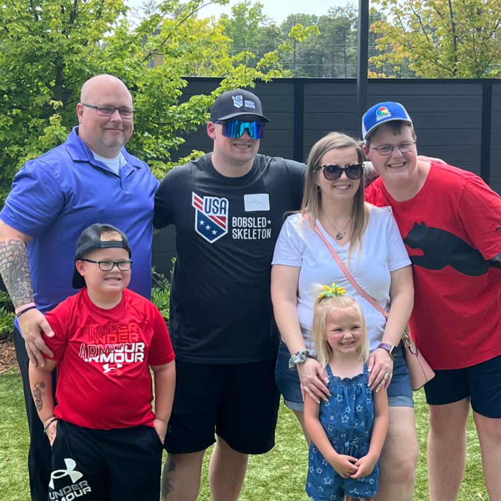 A member of USABS smiles with a family from Take on Sports at the Dream on 3 Topgolf event.