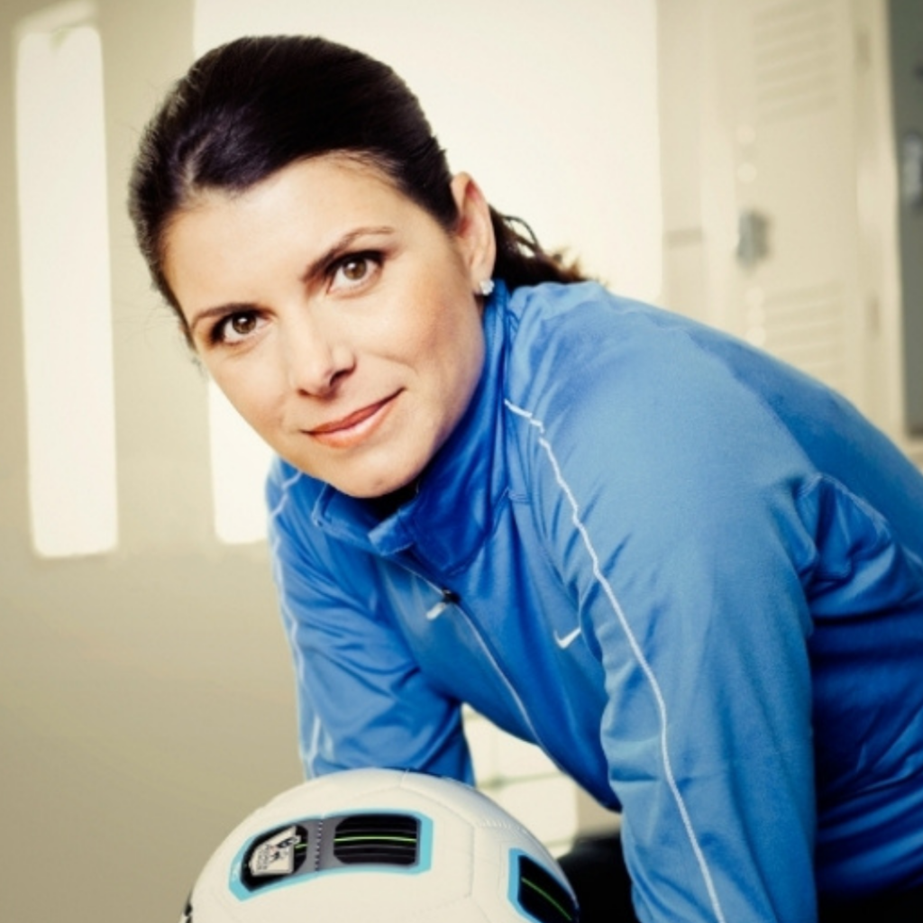 Headshot of AFH Founding Athlete Mia Hamm soft smiling while holding a soccer ball