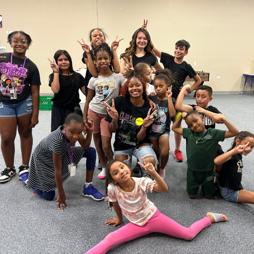 Clark Atlanta basketball player Zion Walters poses with peace signs in the dance studio with clinic participants from the Boys and Girls Club of Greater Phoenix.