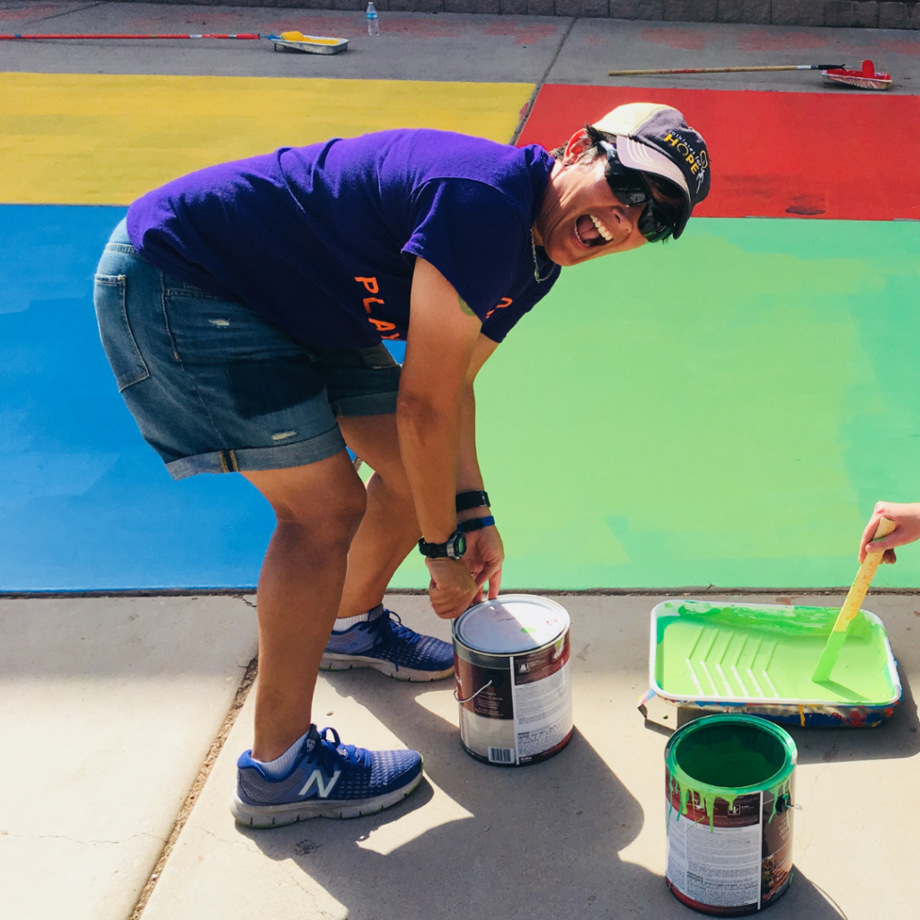 Alex Sachs smiles while opening up a paint during a community service event with Playworks Arizona