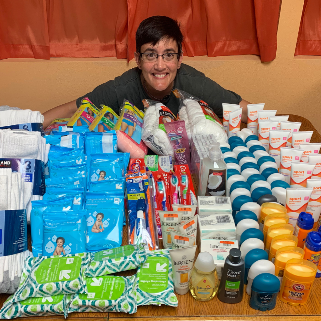 Alex Sachs smiles behind a table full of collected non perishable items