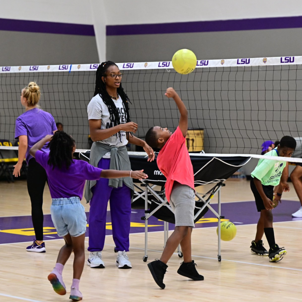 An LSU volleyball team member teachers kids how to volley during Geux Day.