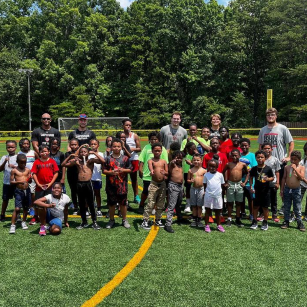 Davidson football players smile for a photo with participants at their football skills clinic.