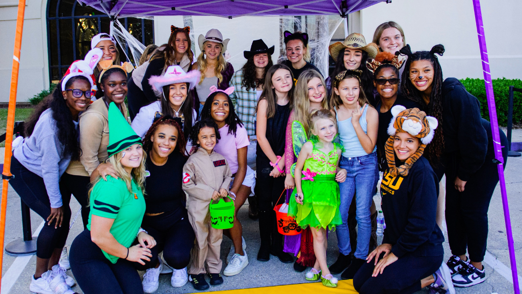 LSU Gymnastics team poses with trick or treaters at the 2022 LSU Halloween Boozar event