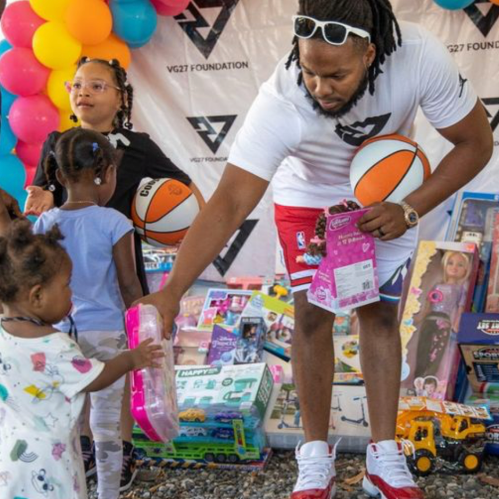 Vladimir Guerrero Jr. passes out a toy to a young Dominican child.