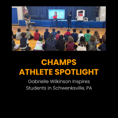 Gabby Wilkinson standing in front of a group of fourth graders in a school gym